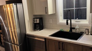 Una cocina moderna con electrodomésticos de acero inoxidable, lavavajillas integrado y armarios de madera.