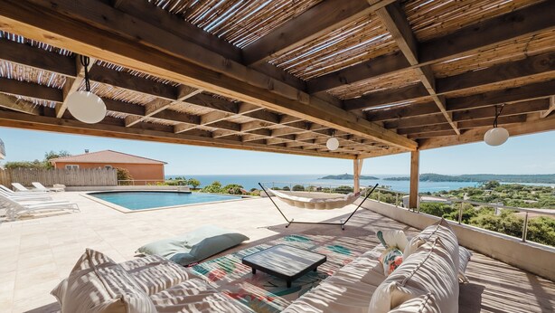 A covered outdoor seating area with a pool, a hammock, and a view of the sea. - Villa de Prestige 460m2, Pinarello, Magnifique vue Mer, Piscine Chauffée (Porto-Vecchio)