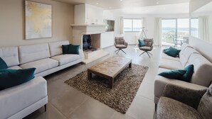 A modern living room with a fireplace, two sofas, a coffee table, and a view of the outdoors. - Villa de Prestige 460m2, Pinarello, Magnifique vue Mer, Piscine Chauffée (Porto-Vecchio)