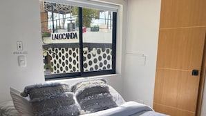 Een slaapkamer met een bed, een raam, een houten deur en een lichtschakelaar.