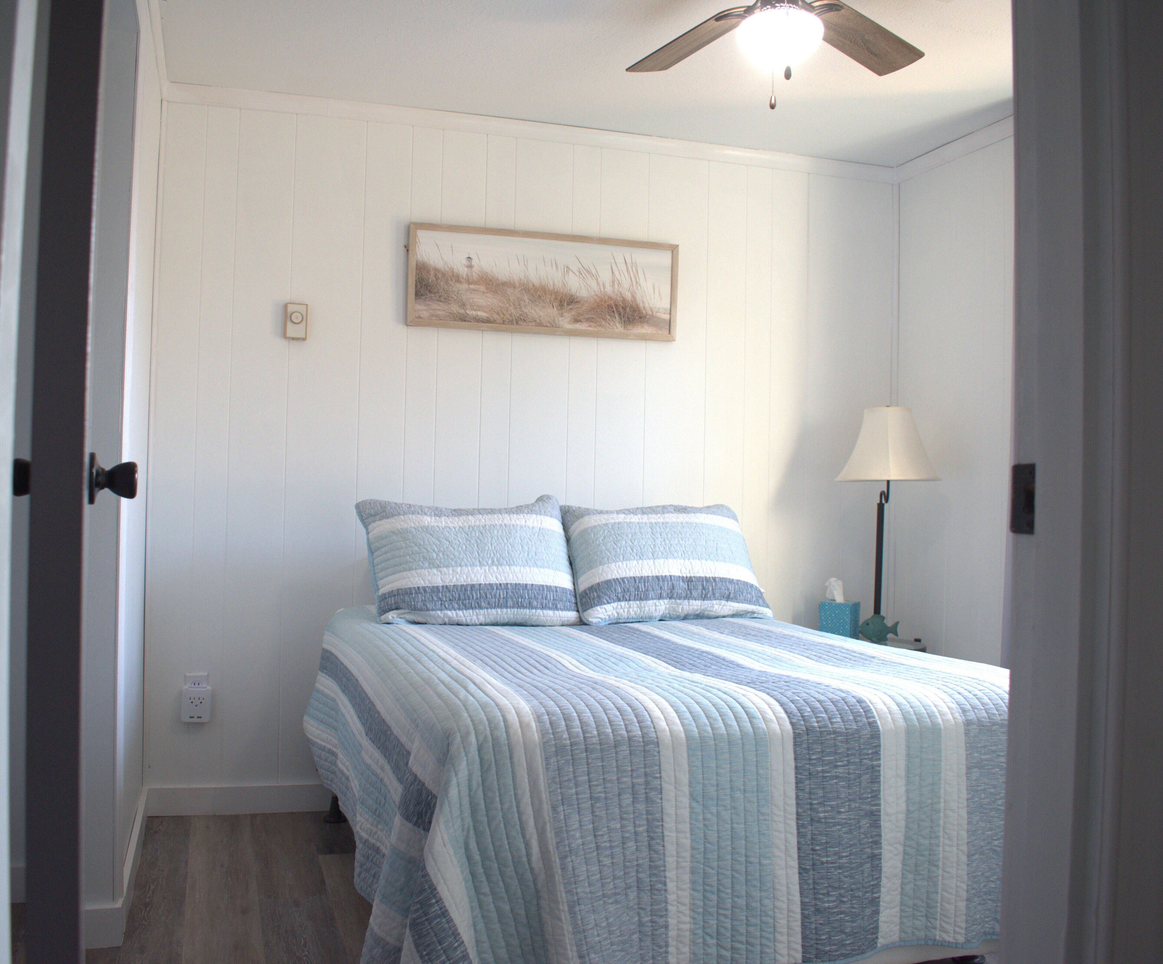 A bedroom with a bed, a nightstand, a lamp, and a ceiling fan.