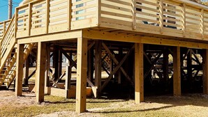 Een houten constructie met balkon, ondersteund door balken en kolommen, in aanbouw.