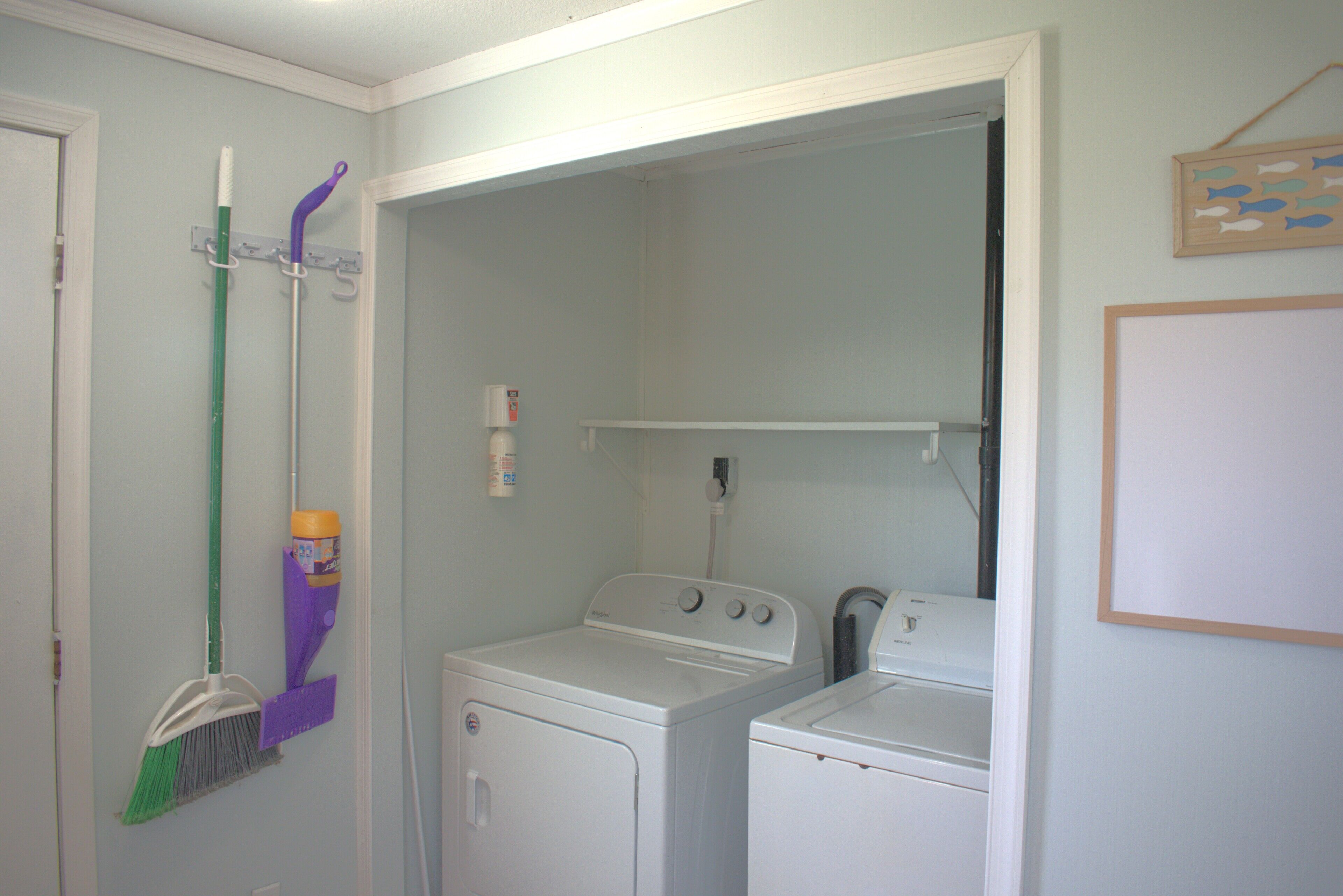 A laundry room with two washing machines, a mopping bucket, and a broom.