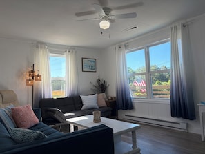 Un salon doté d’un ventilateur de plafond, d’un canapé, d’une table basse et offrant une vue sur l’extérieur.
