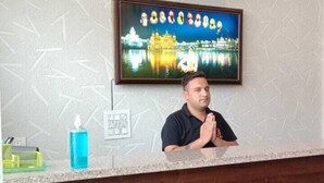 A hotel reception desk with a clock, a framed picture of a building, and a sign above the desk. - Epic Star Hotels and Resorts Amritsar (Amritsar)