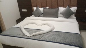 A neatly made bed with a heart-shaped pillow and a blue-striped bedspread. - Epic Star Hotels and Resorts Amritsar (Amritsar)