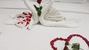A bed with white linens and a decorative swan towel arrangement with a rose. - Epic Star Hotels and Resorts Amritsar (Amritsar)