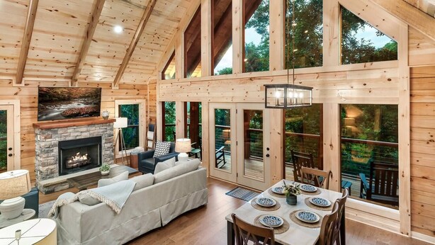 A spacious living room with a fireplace, large windows, and a dining area with a table set for four. - FreeDollywoodTix,HeatedPool,Luxurious,HotTub,Views (Sevierville)