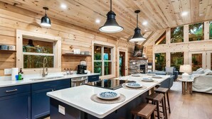 A modern kitchen with wooden walls, a central island, bar stools, and large windows. - FreeDollywoodTix,HeatedPool,Luxurious,HotTub,Views (Sevierville)