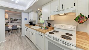 Une cuisine moderne avec des meubles blancs, un four double et un plan de travail en bois.