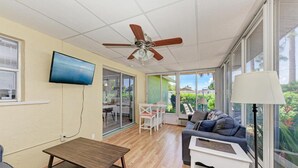 Un vaste espace de vie comprenant un ventilateur de plafond, un téléviseur à écran plat, une table à manger et un canapé.