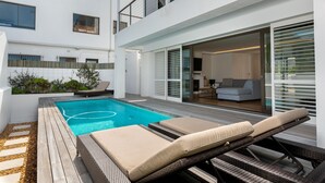 Et moderne poolområde med liggestole og en træterrasse.