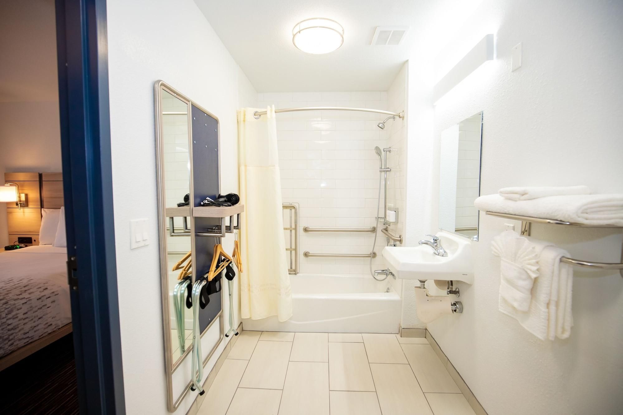Ein Badezimmer im Hotelzimmer mit Dusche, Waschbecken, Spiegel und Handtuchhalter.