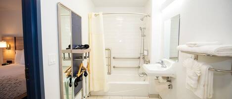 Ein Badezimmer im Hotelzimmer mit Dusche, Waschbecken, Spiegel und Handtuchhalter.