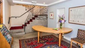 Un intérieur moderne avec un escalier, une table ronde en bois, un tapis à motifs et une chaise.
