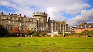 Un grand bâtiment historique, doté d’une tour imposante, entouré d’une pelouse bien entretenue et où quelques personnes se promènent.
