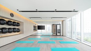 A modern fitness room with exercise mats, a wall-mounted TV, and large windows. - Maqo Changsha  (Changsha)