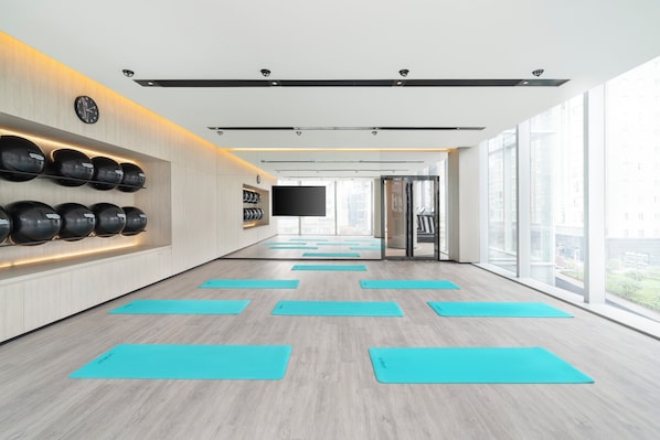 A modern fitness room with exercise mats, a wall-mounted TV, and large windows. - Maqo Changsha  (Changsha)