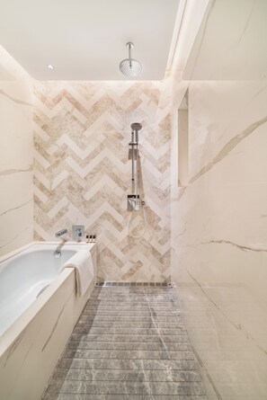 A bathroom with a herringbone-patterned wall, a freestanding bathtub, and a showerhead. - Maqo Changsha (Changsha)