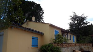 A two-story house with a yellow facade, blue shutters, and a stone wall. - Villa Rénovée, à 5 Minutes du Centre et D'un Supermarché (Cogolin)