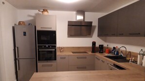 A modern kitchen with a stainless steel refrigerator, double oven, wooden countertop, and a built-in sink. - Villa Rénovée, à 5 Minutes du Centre et D'un Supermarché (Cogolin)