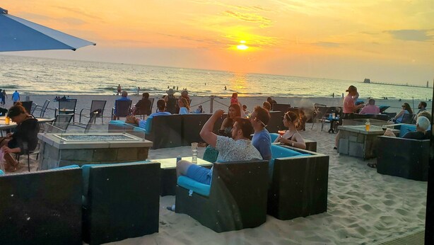 A beachside seating area with tables and chairs, overlooking the ocean and a sunset. - Spacious lakeview home within minutes of beaches, state parks and shopping. (SPRING LAKE)