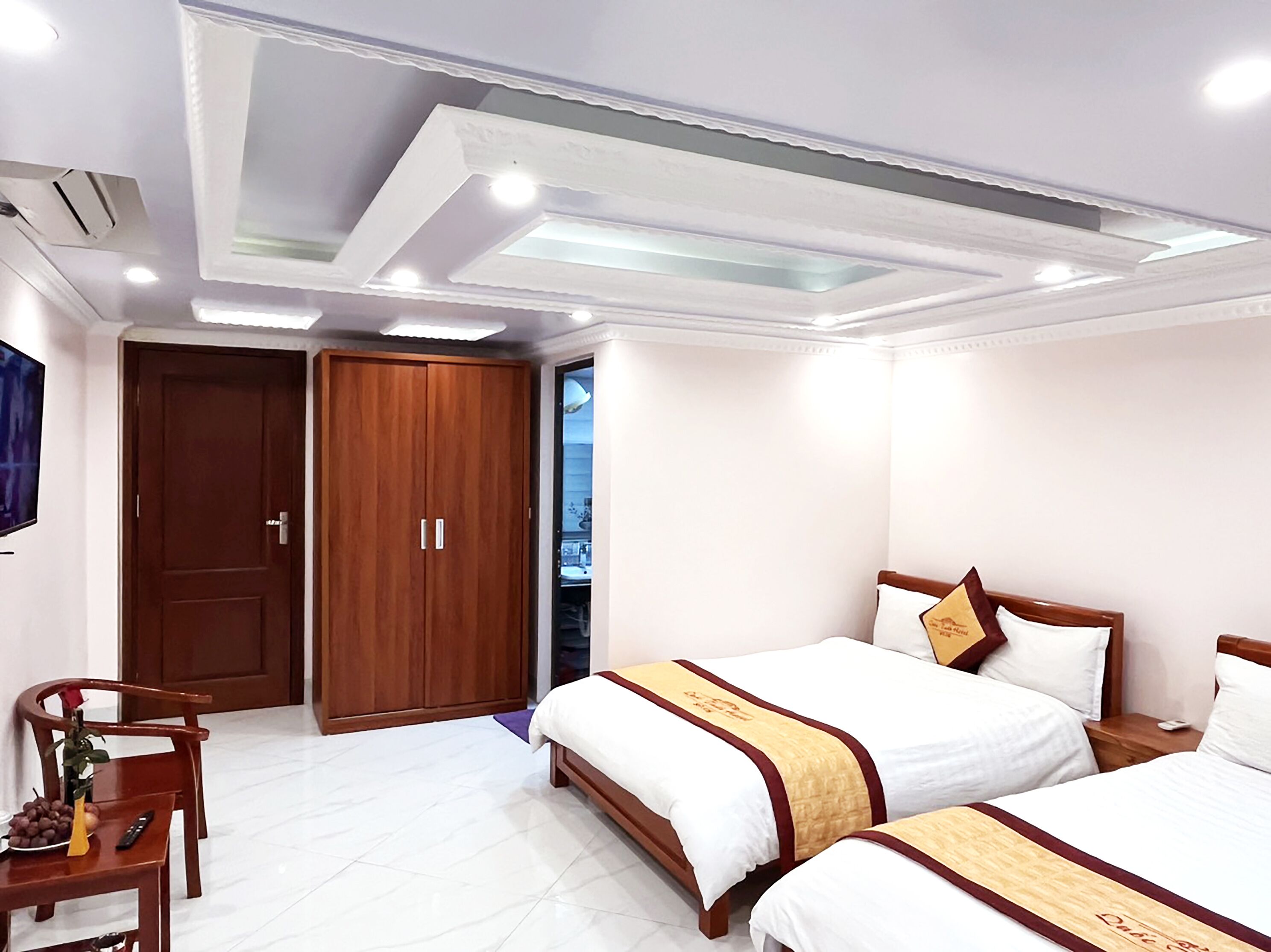 Une chambre d’hôtel avec deux lits, une armoire, un bureau avec une chaise et un téléviseur.