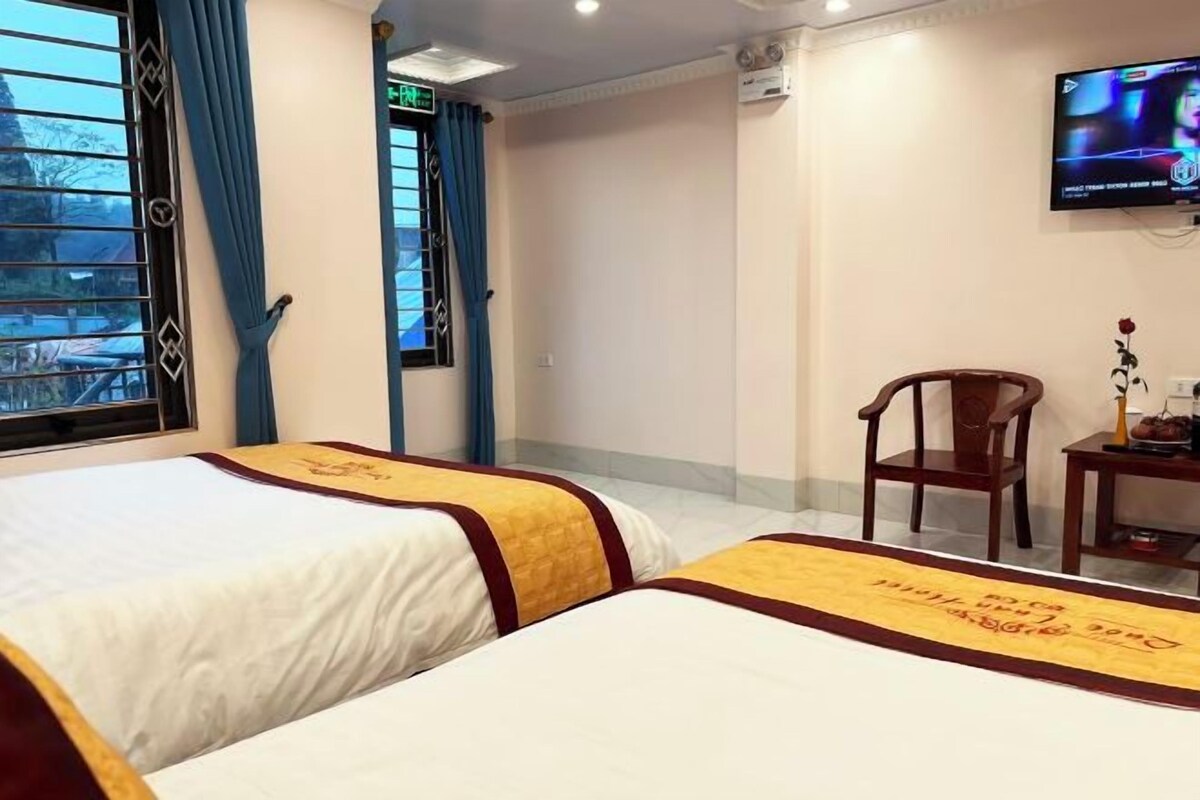 Habitació d'hotel amb dos llits, una televisió, una cadira i una taula petita.