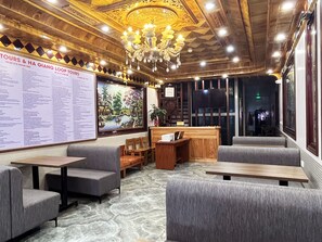 A hotel lobby with a wooden ceiling, a chandelier, a reception desk, and a large menu board. - Quoc Tuan Sapa Hotel (Sa Pa)