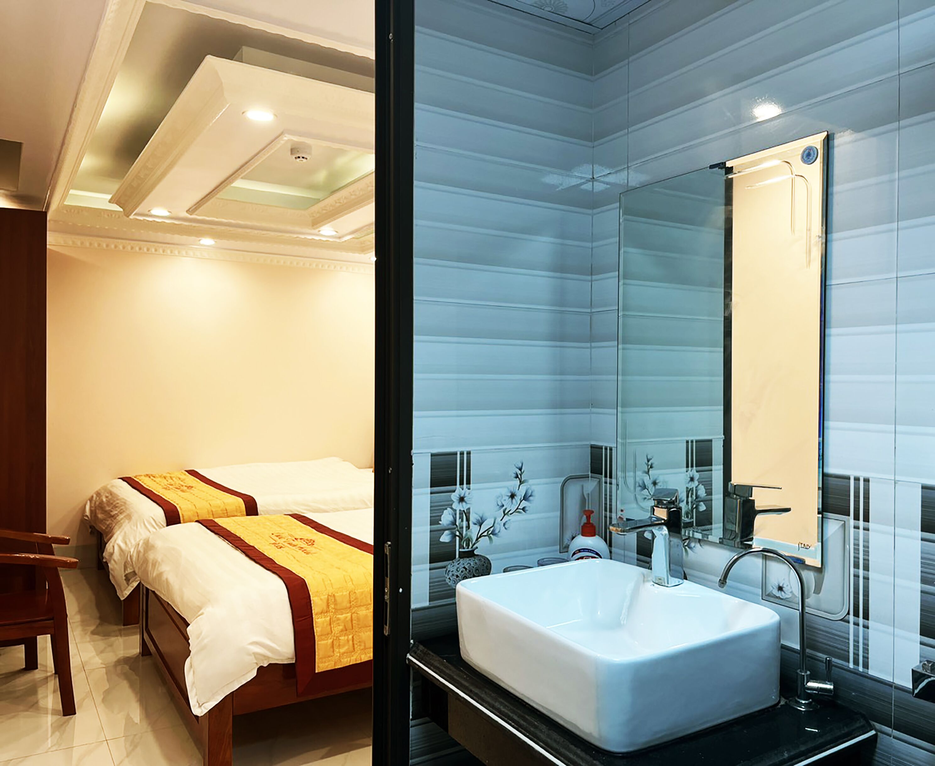 Habitación de hotel con dos camas, un espejo grande, un lavabo blanco y una ventana con vistas.