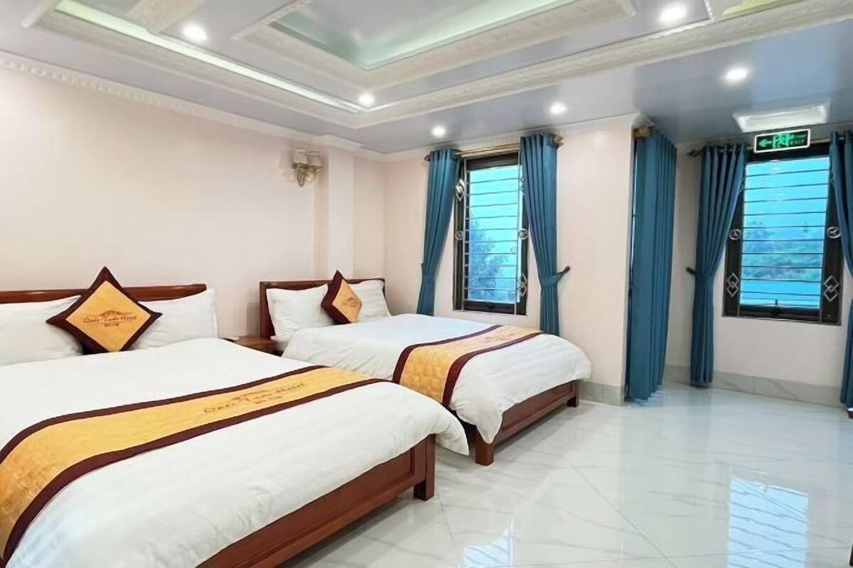 Quarto de hotel com duas camas, um candelabro e vista para o exterior.