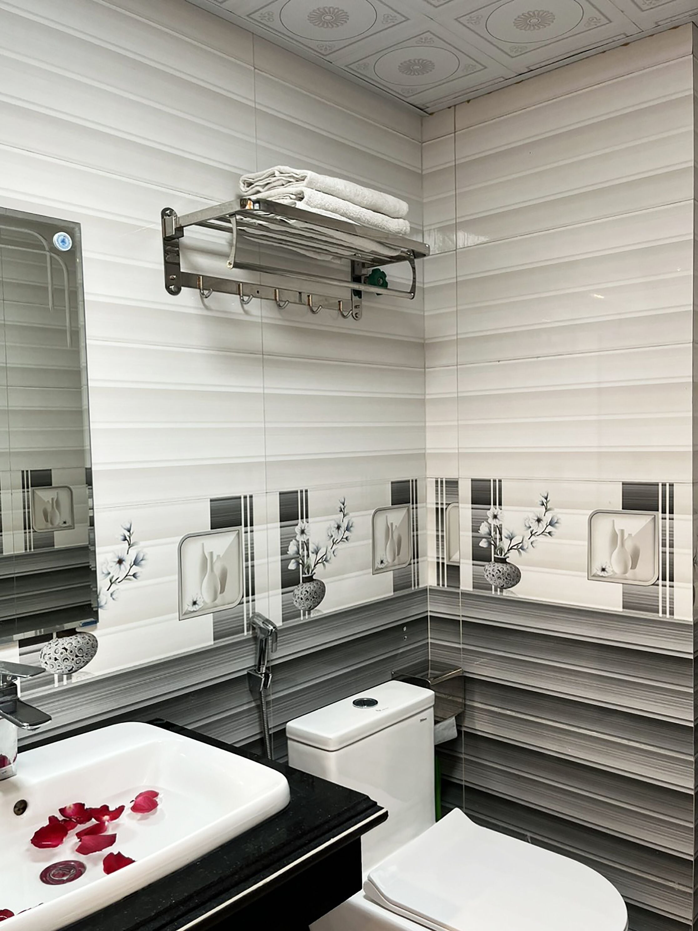 A modern bathroom with a white sink, toilet, and a towel rack above the sink.