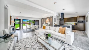 Una sala de estar moderna con una mesa de centro de vidrio, un sofá blanco y vistas al exterior.