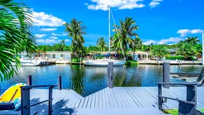 Un puerto deportivo con barcos amarrados, un muelle de madera y palmeras.