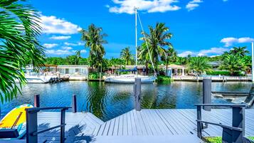 A marina with boats docked, a wooden dock, and palm trees.