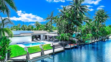 A resort with a swimming pool, a covered patio, and a dock extending into the water.