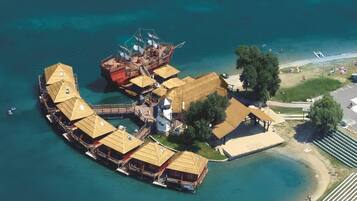 An aerial view of a waterfront property with multiple overwater bungalows, a central building, and a beach area.