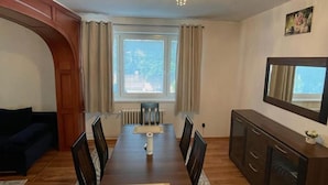 Un coin repas comprenant une table en bois, des chaises, un radiateur et un meuble.