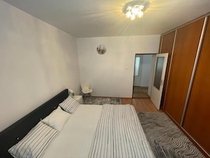 Une chambre d’hôtel avec un lit, une chaise, une armoire et un miroir.
