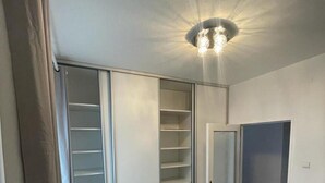 Une pièce avec un luminaire au plafond, une porte coulissante de placard et une porte fermée.