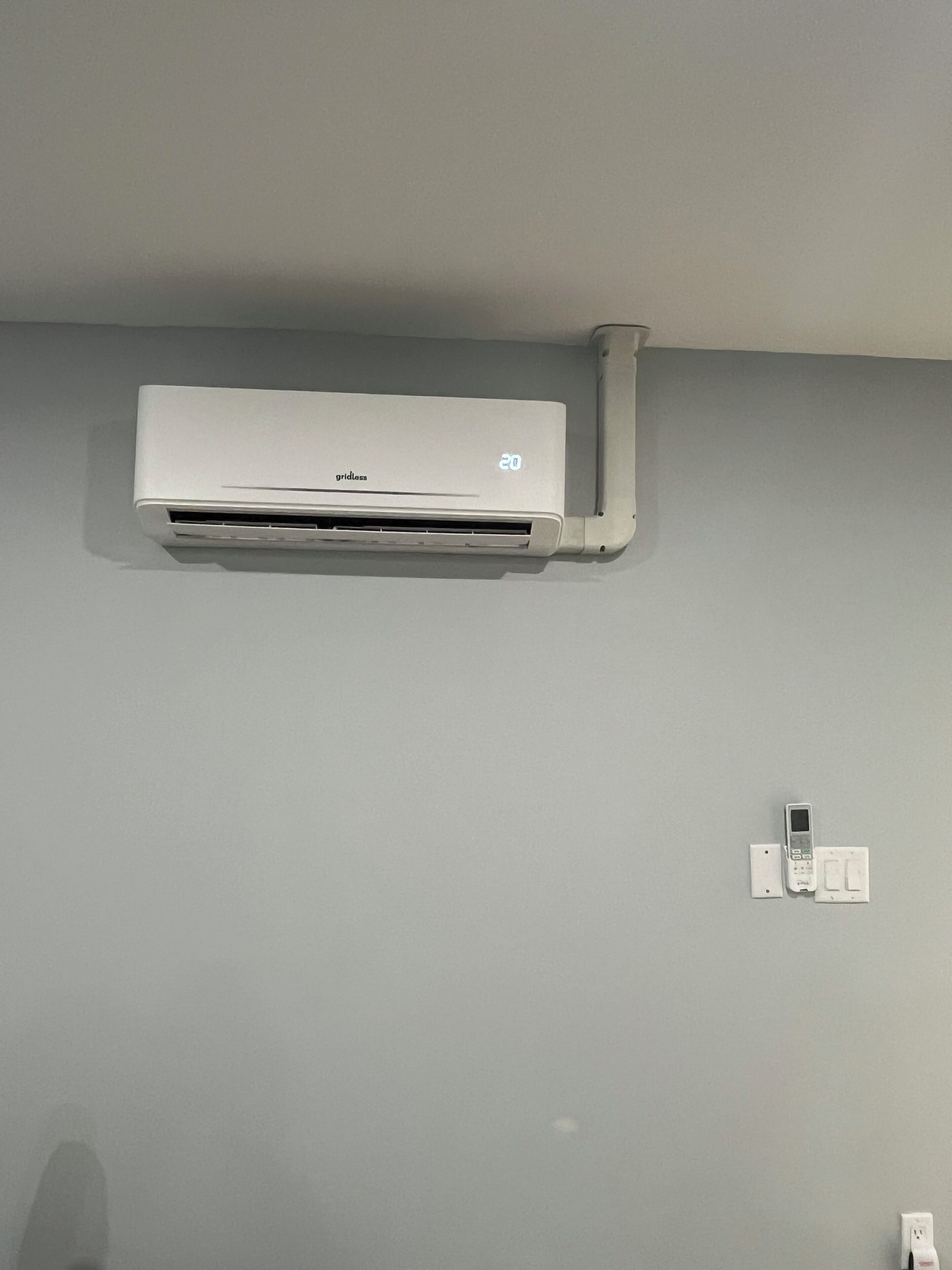 Un appareil de climatisation blanc fixé au mur, une prise de courant et une fiche électrique.