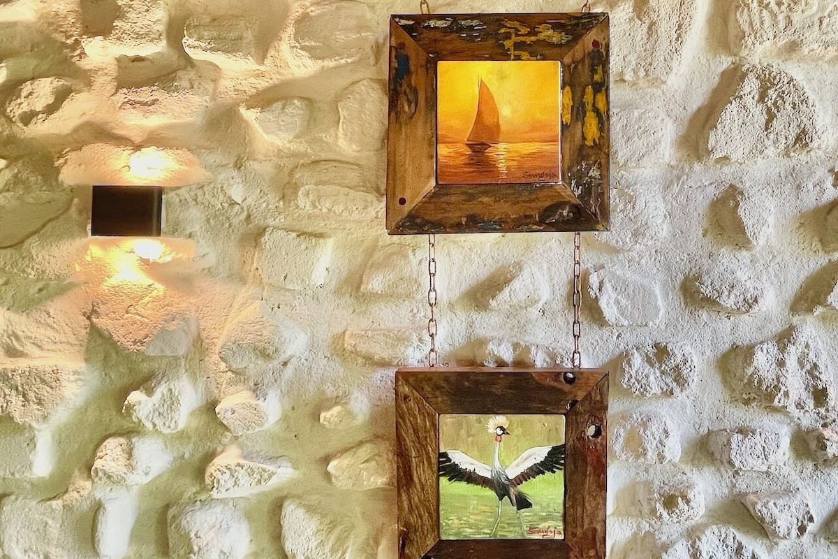 Two wooden picture frames with paintings on a textured wall.