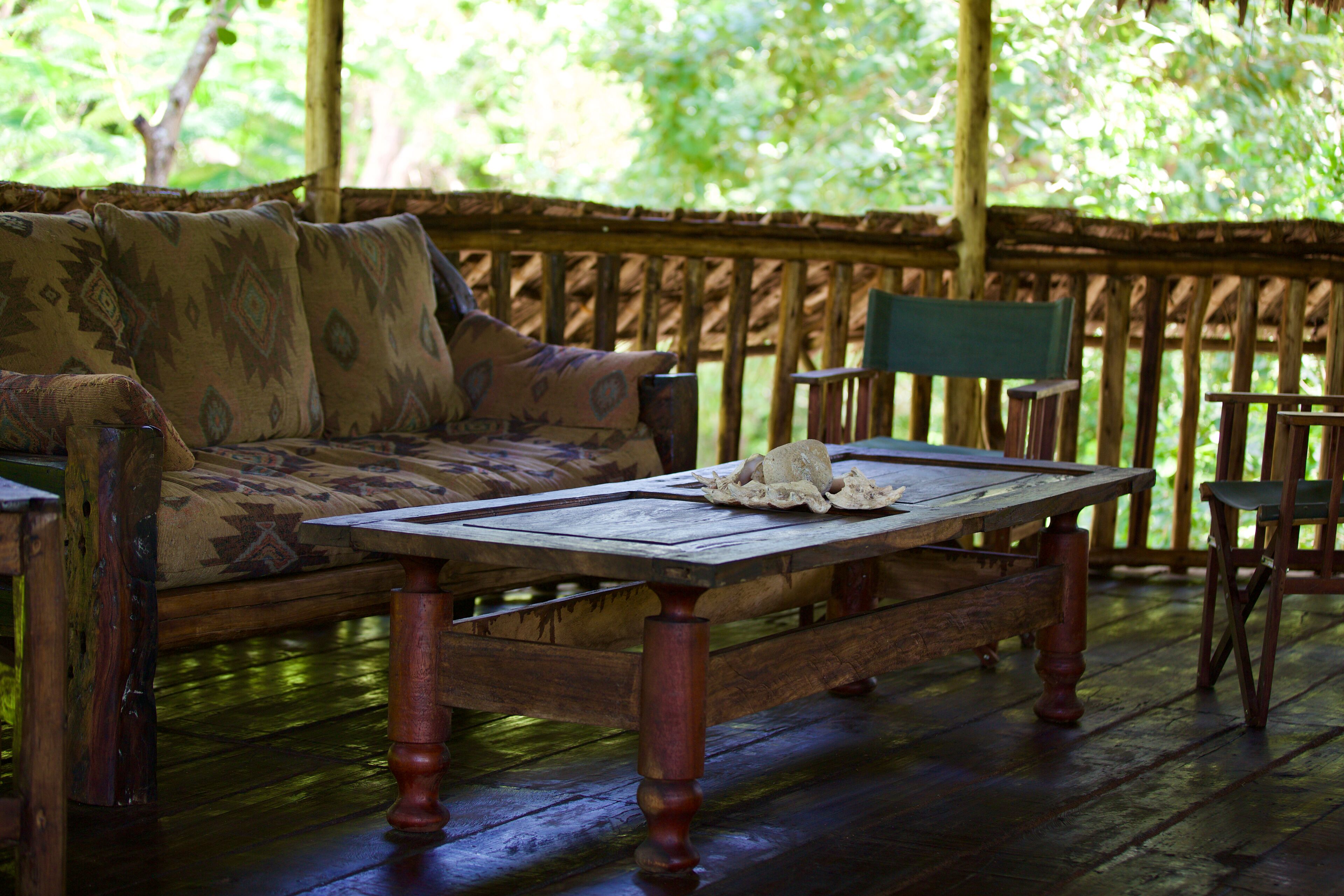 A wooden deck with a sofa and a table, surrounded by wooden railings.