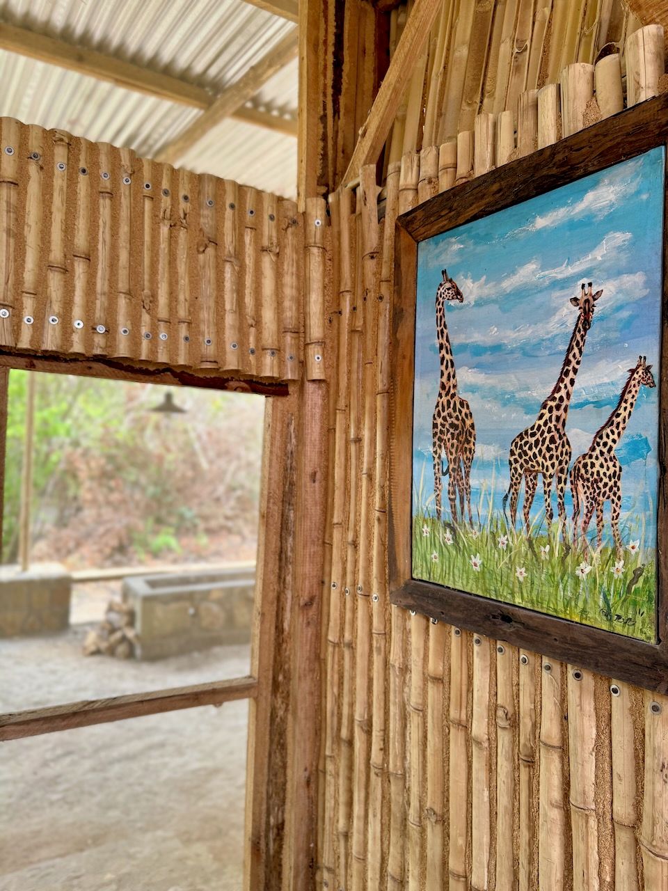 A room with bamboo walls and a painting of giraffes.