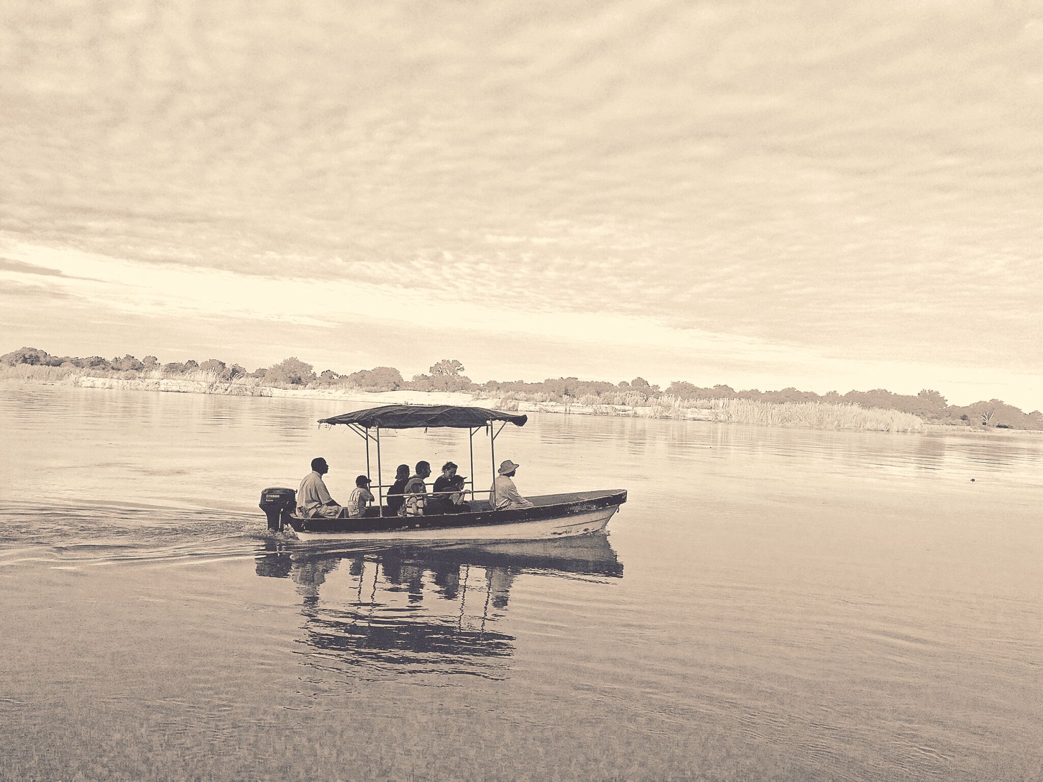 A boat with a canopy, passengers, and calm water.