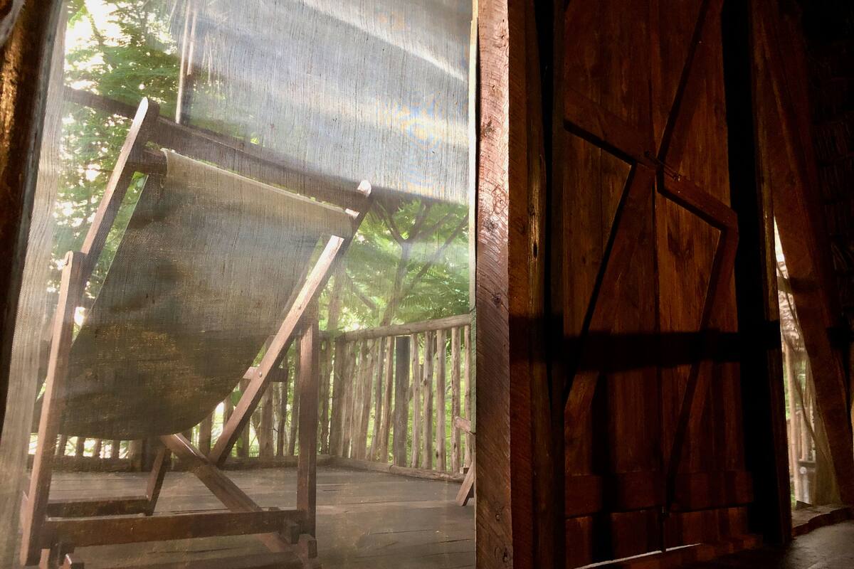 A rustic wooden structure with a slanted roof and a wooden bench.