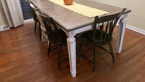 Een eettafel met een placemat en een pompoen als middelpunt, omringd door stoelen.
