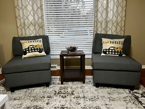 Relax in this inviting living room with two comfortable armchairs, a side table, and a potted plant.