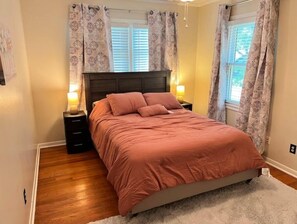 Cozy retreat with a large bed, nightstands, and a window with curtains.