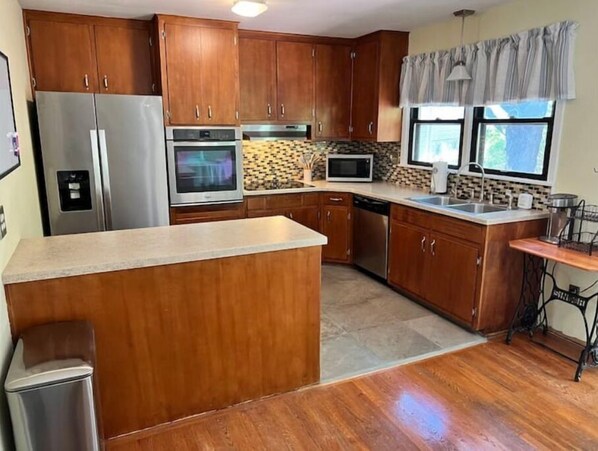 Enjoy cooking in this well-equipped kitchen with a central island, stainless steel appliances, and a tiled backsplash.